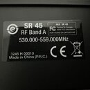 Fotografie detailně zobrazuje černý štítek s bílými nápisy. Je na něm uveden model SR 45, označení RF Band A a frekvenční rozsah 530.000-559.000MHz.…