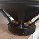 Fotografie zachycuje detail spodní části černého reproduktoru. Jsou vidět kovový rám, zapojovací svorky a magnet s gumovým těsněním. Na pravé straně…