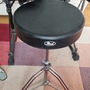 Černý bubeníckýstolek s kulatým polstrovaným sedadlem z imitace kůže. Na přední straně sedadla je bílé logo Pearl. Podnoží je trojnohé, vyrobené z ch…