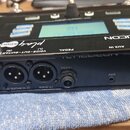 Černý procesor efektů s nápisy TC HELICON a play acoustic. Na zadním panelu jsou vstupy a výstupy s popisky POWER 12 V = 400 mA, GUITAR DI (R), VOICE…
