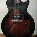 Elektrická kytara s tmavě hnědým gradientem (sunburst) a černým pickguardem. Nástroj má jeden humbucker snímač u kobylky a dva ovládací knoflíky. Na…