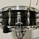 Černý snare drum s chromovaným kováním a obručemi. Na mechanismu napínání je viditelný nápis YAMAHA. Povrch nástroje je glossy a v dobrém stavu bez v…