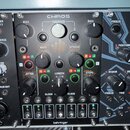 Černý modul s nápisem CHAOS a logem behringer v dolní části. Zařízení obsahuje několik otočných potenciometrů s popisky BIAS, FEEDBACK, RATE, SPREAD,…