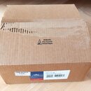Hnědý kartonový krabic s viditelným poškozením v horní části, kde je roztržený povrch. Uprostřed je černý varovný nápis s ikonou: BEWARE May Contain…