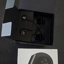 Černé špunty do uší v otevřené černé krabici. Vedle krabice je položen bílý manuál s fotografií sluchátka a nápisy audio-technica a ATH-E40. Povrchy…
