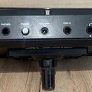 Zadní strana černého elektronického bicího padu s nápisem ALESIS SAMPLEPAD 4. Jsou zde viditelné konektory s popisky PHONES, POWER, 9V DC 500mA, TRIG…