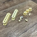 Sada plastových dílů pro kytaru v krémové barvě. Obsahuje dva oválné pickguardy s otvory, tři otočné knofíky s nápisy TONE, TONE a VOLUME včetně číse…