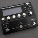 Černý kytarový efektový procesor s displejem a pěti stříbrnými ovládacími knoflíky. Na horní hraně je nápis BOSS GT-1000CORE GUITAR EFFECTS PROCESSOR…