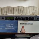 Šedý rackový procesor s nápisem VOICEWORKS a logem TC-HELICON. Zařízení má digitální displej, několik tlačítek, dva otočné ovladače a konektory na za…