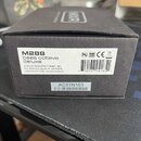 Černá kartonová krabice s bílou nálepkou. Na nálepce je uveden model M288 bass octave deluxe a text DUNLOP MANUFACTURING, INC. P.O. BOX 846, BENICIA,…