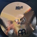 Kulatý mosazný činel s kladivkovaným povrchem. Na horní části je černý nápis Mb10 a pod ním text 16" Medium Crash, v horní části je viditelné logo ME…