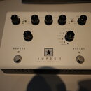 Bílý efekt pedál s nápisem AMPED 1 a podtitulem DEPT. 10 | 100W AMP PEDAL. Uprostřed je logo ve tvaru černé hvězdy v bílém čtverci. Zařízení má šest…