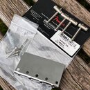 Sada chromovaných komponentů pro kobylku elektrické kytary v originálním balení. Na černém kartonu jsou čtyři chromované strunníky a nápisy Genuine F…