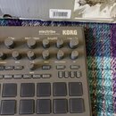 Šedý sampler KORG electribe MUSIC PRODUCTION STATION. Zařízení obsahuje několik otočných potenciometrů s popisky jako Filter, Modulation, Amp/EG a In…
