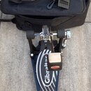 Na fotografii je černá textilní taška s červenobílým logem Gibraltar a modrý skateboard se stříbrnými vlnitými pruhy. Na prkně je bílý nápis Gibralta…