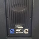 Zadní panel černého aktivního reproduktoru. V horní části jsou vstupy INPUT a THRU, kontrolky CLIP/TEMP, SIGNAL, STATUS a tlačítko PRESET SELECT s vý…