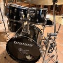 Černá bicí souprava s chromovaným hardwarem. Na předním obalu basového bubnu je bílé logo ludwig a pod ním černobílý nápis BICI CZ s nečitelným texte…