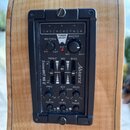Detail na černý předzesilovač vestavěný do dřevěného těla akustické kytary. Na panelu jsou nápisy „Alvarez“ a „System 600T MK II“. Zařízení obsahuje…