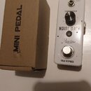 Bílý efekt pedál s nápisy NOISE GATE, Rowin a TRUE BYPASS. Obsahuje jeden ovládací knoflík s popiskem THRESHOLD a přepínač s označením HARD / SOFT. V…