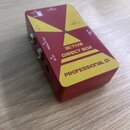 Červený kovový box s žlutými trojúhelníkovými prvky. Na horní straně jsou nápisy ACTIVE DIRECT BOX, PROFESSIONAL DI a značka Casine. Jsou zde vidět v…