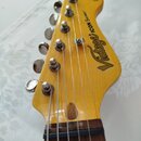 Zadní strana hlavy elektrické kytary z jasně žlutého dřeva s chromovanými ladicími kolíky. Na povrchu je černý nápis „Vintage® ICON Series™“. V horní…