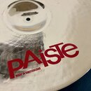 Kovový činel stříbrné barvy s jemným žebrováním povrchu. Na ploše je červený nápis PAiste a pod ním menší červený text MADE IN SWITZERLAND. V horní č…