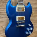 Modrá elektrická kytara s charakteristickým SG tvarem korpusu. Nástroj má dva humbuckery s krémovými rámečky, chromovaný kobylník a čtyři ovládací kn…