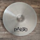 Kruhový činel z kovového materiálu s matným povrchem. V dolní části je černý nápis pAiste a pod ním menší text MADE IN SWITZERLAND. V horní části je…