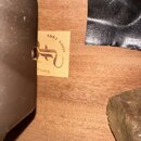 Detailní záběr na dřevěný povrch s přilepeným malým žlutým štítkem. Na štítku je hnědý stylizovaný symbol a nápisy „since 1981“ a „furch“. V levé čás…