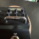 Detailní pohled na černý kytarový pedál s kovovou rukojetí. Na horní části jsou vidět čtyři černé ovládací knoflíky a nápis OR TYPE. Ve spodní části…