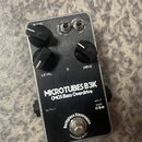 Kovový efekt pedál stříbrné barvy s černými ovládacími knoflíky. Na spodní části je nápis MICROTUBES B3K CMOS Bass Overdrive a v dolní části logo Dar…