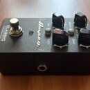 Černý basový předzesilovač v kovovém boxu s nápisy CLASSIC Analog Bass Preamp a logem Ampeg. Na horní straně jsou čtyři černé ovládací knoflíky s bíl…