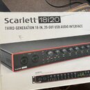 Fotografie znázorňuje kartonovou krabici s produktem Scarlett 18i20. Na krabici je nápis „Scarlett 18i20 THIRD-GENERATION 18-IN, 20-OUT USB AUDIO INT…