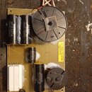 Fotografie znázorňuje elektronickou desku s osazenými komponenty. Na desce jsou čtyři černé válcové kondenzátory s bílým nápisem BENNIC, dva z nich m…