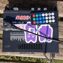 Černý audio zesilovač s nápisem +300W, HiFi DIGITAL a REO AUDIO POWER AMPLIFIER. Zařízení je polepeno dvěma fialovými nálepkami ve tvaru duchů, z nic…