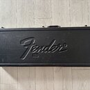 Černý obdélníkový kufřík s rukojetí a kovovými rohy. Uprostřed víka je vyražený nápis Fender® a pod ním v malém obdélníku nápis USA. Povrch vykazuje…