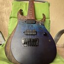 Elektrická kytara s trupem v modročerné barvě a viditnou strukturou dřeva. Nástroj má dva humbuckery, jeden ovládací knoflík a jeden přepínač. Kobylk…