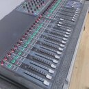 Šedočerný mixovací pult s posuvníky a řadou ovládacích knoflíků. V levém horním rohu je bílý nápis Soundcraft a vedle něj označení modelu SX. Zařízen…