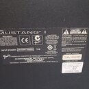 Fotografie zachycuje detail štítku na zadní straně přístroje. Na štítku je velkým písmem nápis MUSTANG™ I a logo Fender. Jsou zde uvedeny technické ú…