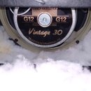 Fotografie zachycuje reproduktor s nápisy G12, Vintage 30 a CELESTION INTERNATIONAL LTD. V horní části je vidět část skříně s nápisem 8Ω MONO a bílý…