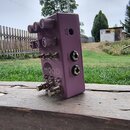Fialový efekt pedál s nápisem MOOD na přední straně. Na pravém boku jsou umístěny konektory s popisky 9 V DC, EXP / CV a IN (STEREO). Horní strana ob…