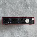 Červené audio rozhraní s kovovým povrchem. Na zařízení jsou nápisy Scarlett 2i4, LINE INST, PAD, GAIN, MIDI, 48V, INPUT, PLAYBACK, DIRECT MONITOR, ST…