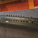 Zadní panel černého elektronického zařízení s nápisem "and" v levé části. Panel obsahuje řadu ovládacích knoflíků a konektory s popisky: "MIC/LINE IN…