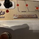 Detailní pohled na ovládací panel zařízení s béžovým povrchem. Je zde vidět část nápisu "nde DELUXE", tři červené kontrolky a nápisy "BANK", "PUSH 2X…