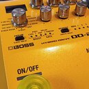 Žlutý kytarový efekt s nápisy BOSS, HYBRID DRIVE a OD-200. Zařízení má několik kovových otočných ovladačů, tlačítka PARAM, BOOST a GATE s doprovodným…