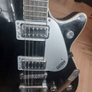 Černá elektrická kytara s dvěma snímači v chromovaných rámečcích. Na stříbrném plechu (pickguardu) je nápis GRETSCH ELECTROMATIC. Nástroj má chromova…