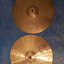 Dva mosazné činely typu hi-hat položené na modrém podkladu. Oba mají vyražený nápis SOUND FORMULA. Horní činel je hladký s nápisem Medium Heavy Hi-Ha…