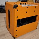 Kytarový kombozesilovač v oranžovém texturovaném potahu s černými plastovými rohy a úchytem. Na horní části je ovládací panel s knoflíky a přepínači,…