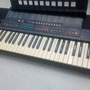 Černý elektronický klavír s bílými a černými klávesami. Na levé straně je bílé logo YAMAHA a na pravé straně nápis PSR-215. Horní panel obsahuje řadu…