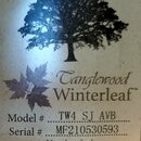 Fotografie štítku s nápisy a grafikou stromu a listu. Je zde uveden název Tanglewood Winterleaf™, Model # TW4 SJ AVB a Serial # MF210530593. Dole je…